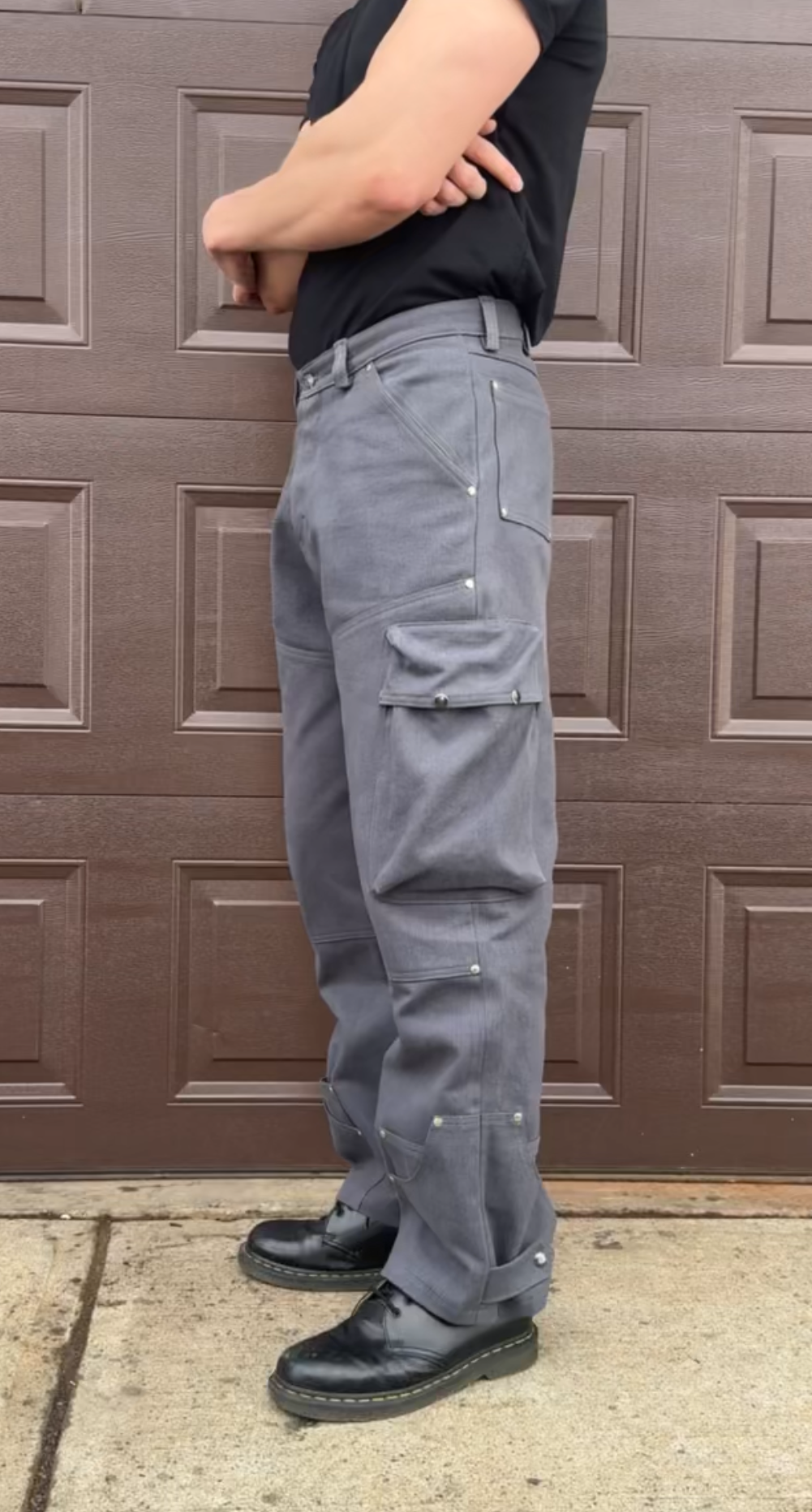 Person wearing gray cargo pants standing in front of a brown garage door.